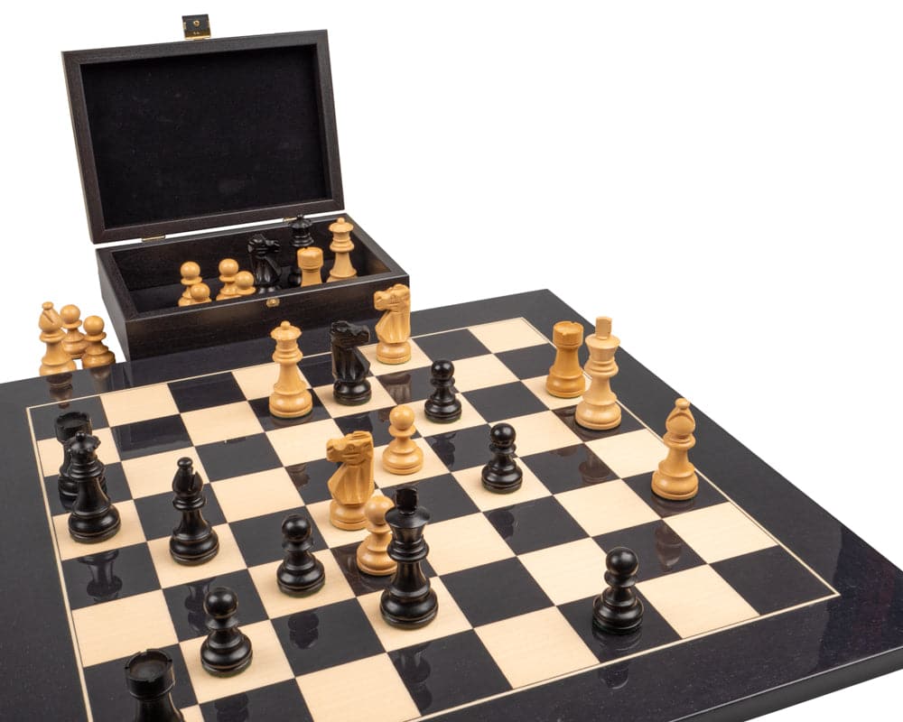 The French Knight Luxury Black Chess Set with wooden pieces on a black and beige board and an open matching box in the background.