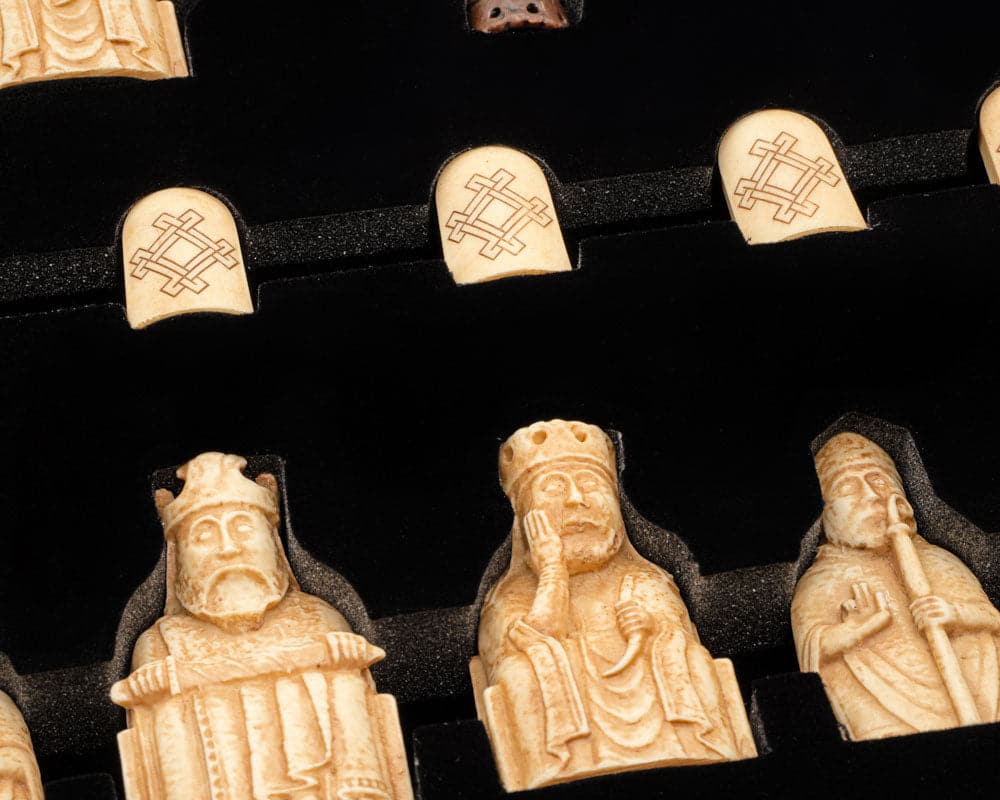 Isle of Lewis Chessmen pieces displayed in foam tray, showcasing detailed and intricately carved designs by Italian craftsmen.