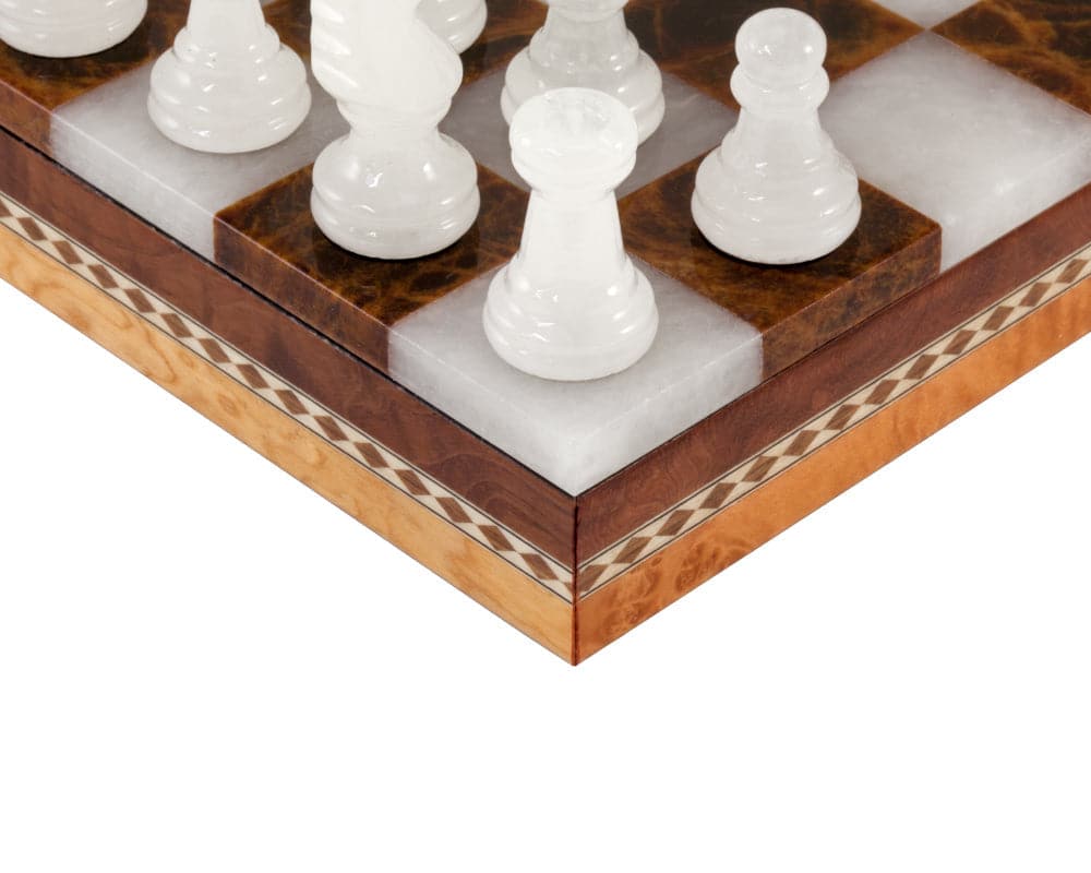 Close-up of white alabaster chess pieces on brown and white inlaid alabaster chessboard with wooden cabinet edge by Scali Alabastro.
