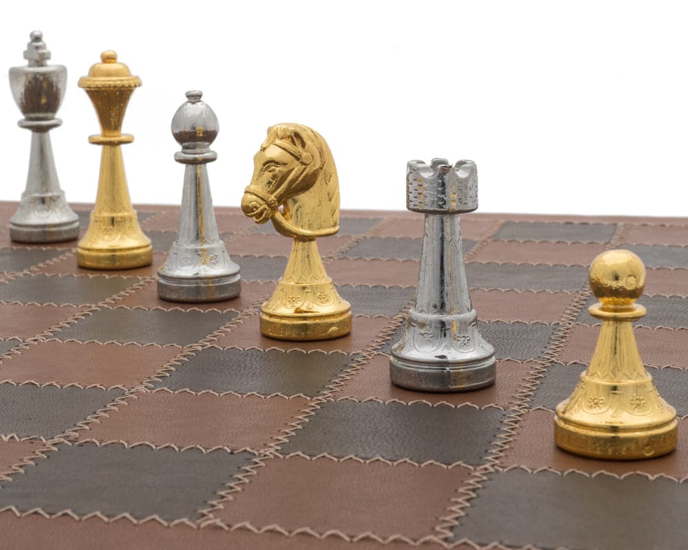 Gold and silver chess pieces on Italian leather chessboard.
