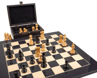 The French Knight Luxury Black Chess Set with wooden pieces on a black and beige board and an open matching box in the background.